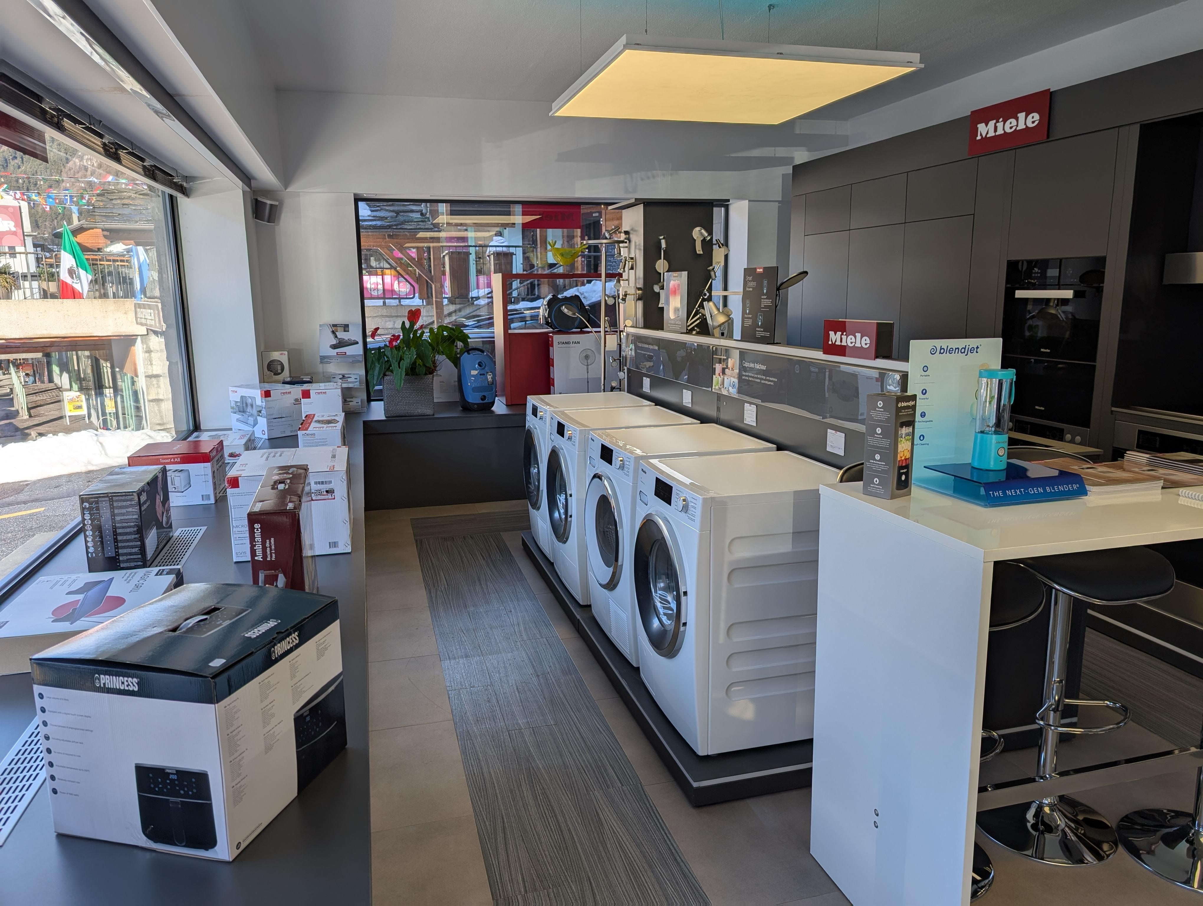 Showroom lumineux d'un spécialiste en électroménager valaisan, présentant des appareils Miele et Nespresso sur des surfaces en bois clair, ambiance chaleureuse et alpine